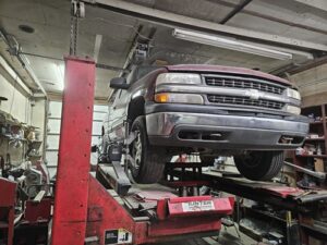 Chevrolet truck elevated on a red tire alignment rack in an automotive service shop, illustrating wheel alignment services offered by Leo Tire & Wheel.
